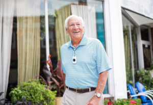 Man in blue shirt, smiling, enjoying a walk down the street with CoxHealth Lifeline securely hanging on a lanyard around his neck